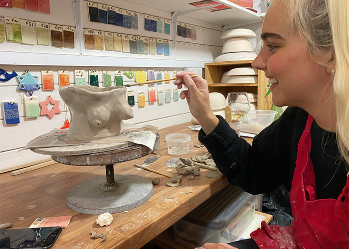 young women painting ceramic work of art 