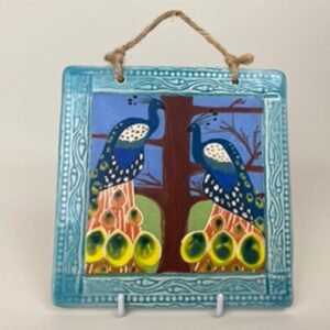 A handmade earthenware hanging wall tile. This tile design of the peacock symbolises nobility and protection.