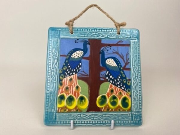 A handmade earthenware hanging wall tile. This tile design of the peacock symbolises nobility and protection.