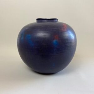 A handmade earthenware coiled pot, colored deep blue, with a cobalt blue glaze on the interior, inspired by the humble blueberry. 